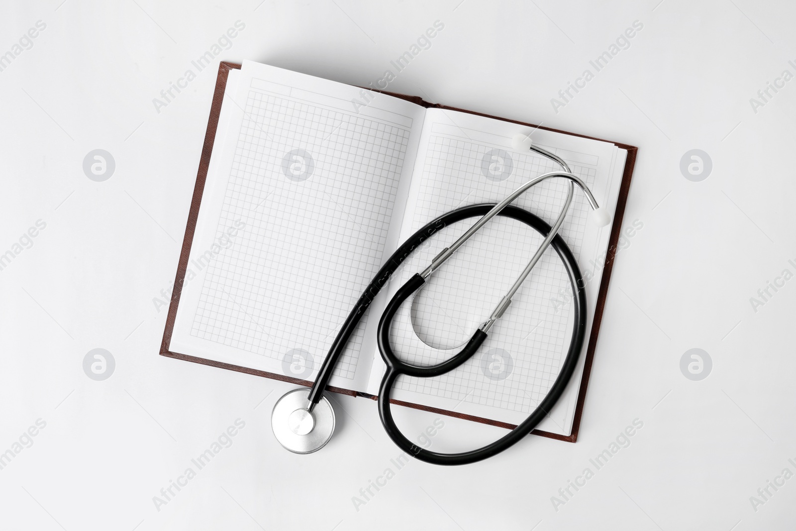 Photo of Stethoscope and open notebook with space for text on white background, top view. Medical students stuff