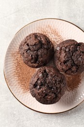 Photo of Delicious chocolate muffins and cacao powder on light grey table, top view
