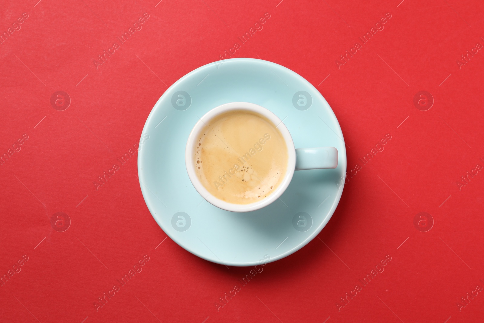 Photo of Aromatic coffee in cup on red background, top view