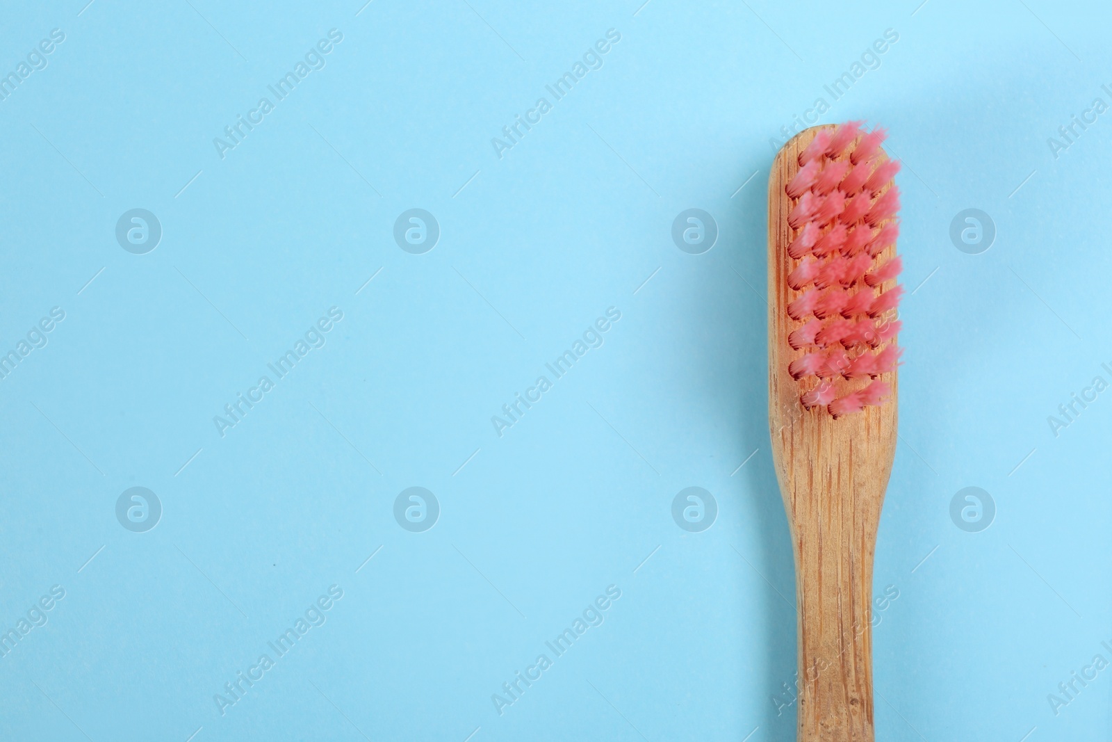 Photo of Toothbrush made of bamboo on light blue background, top view. Space for text