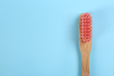 Photo of Toothbrush made of bamboo on light blue background, top view. Space for text