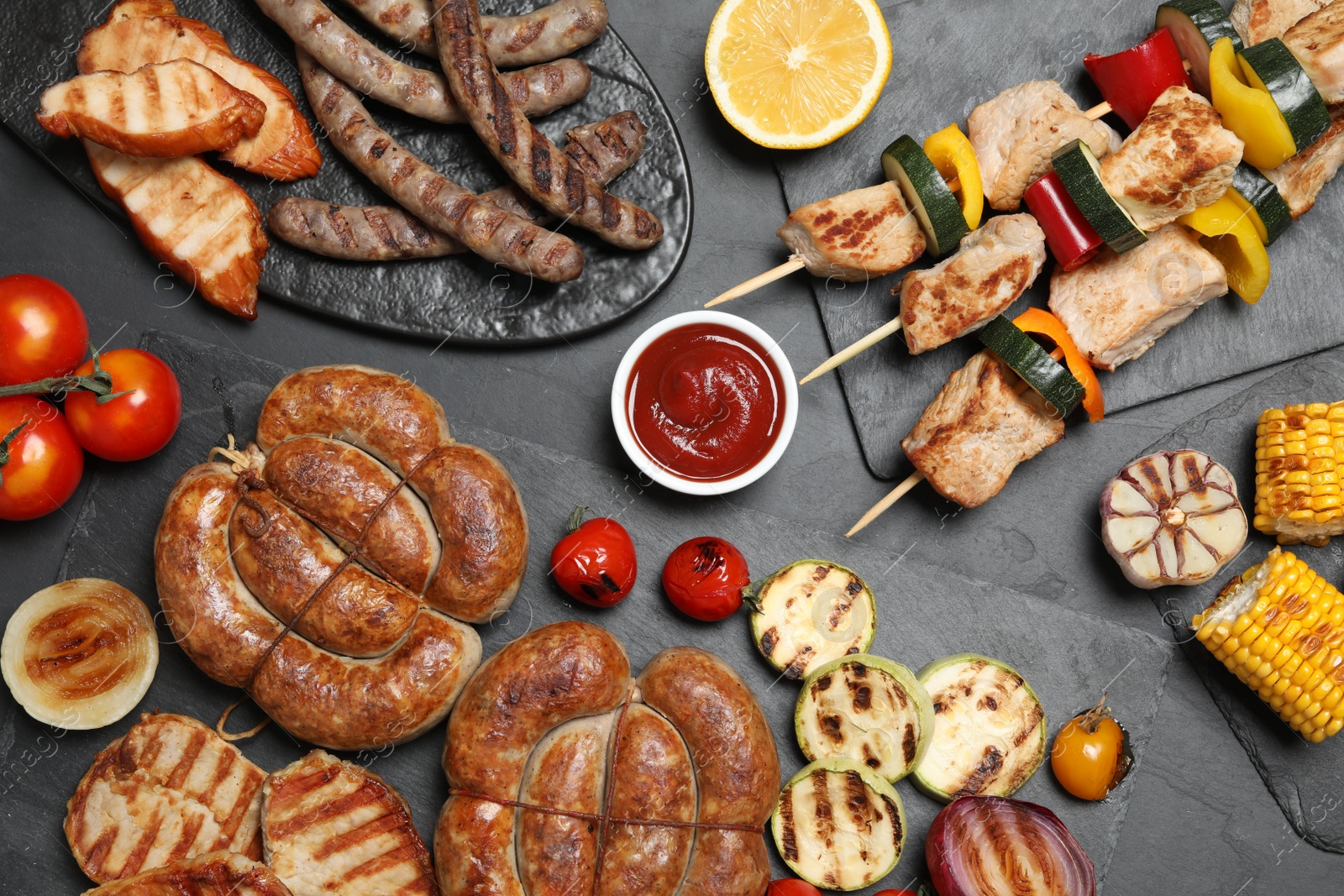 Photo of Flat lay composition with barbecued meat and vegetables on grey table