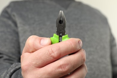 Man with green combination pliers, closeup view