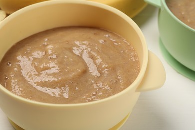 Photo of Baby food. Bowl with banana puree on white table, closeup