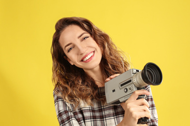 Photo of Beautiful young woman with vintage video camera on yellow background