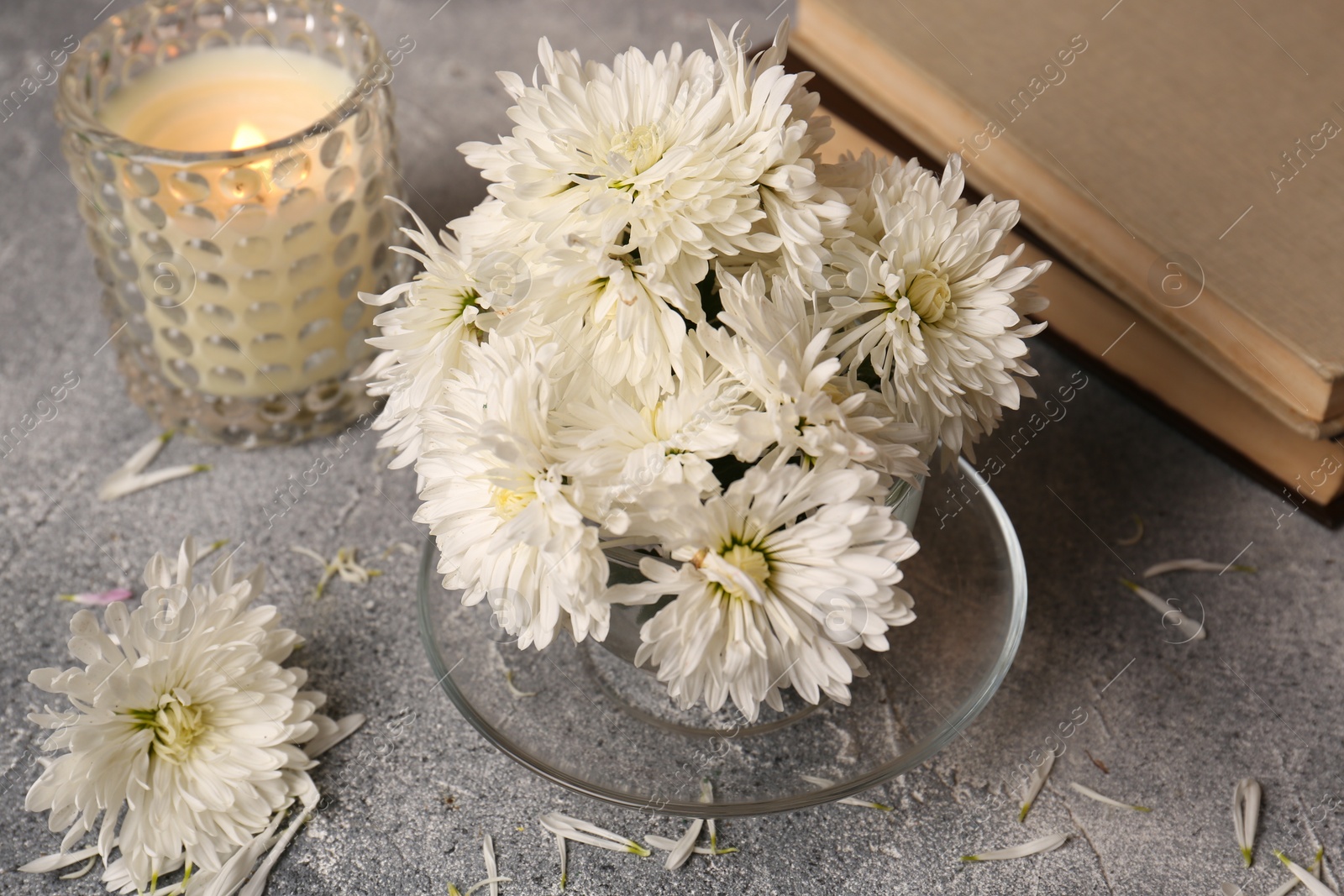 Photo of Composition with chrysanthemum flowers, books and candle on grey textured table