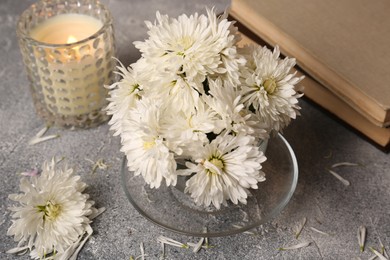 Composition with chrysanthemum flowers, books and candle on grey textured table