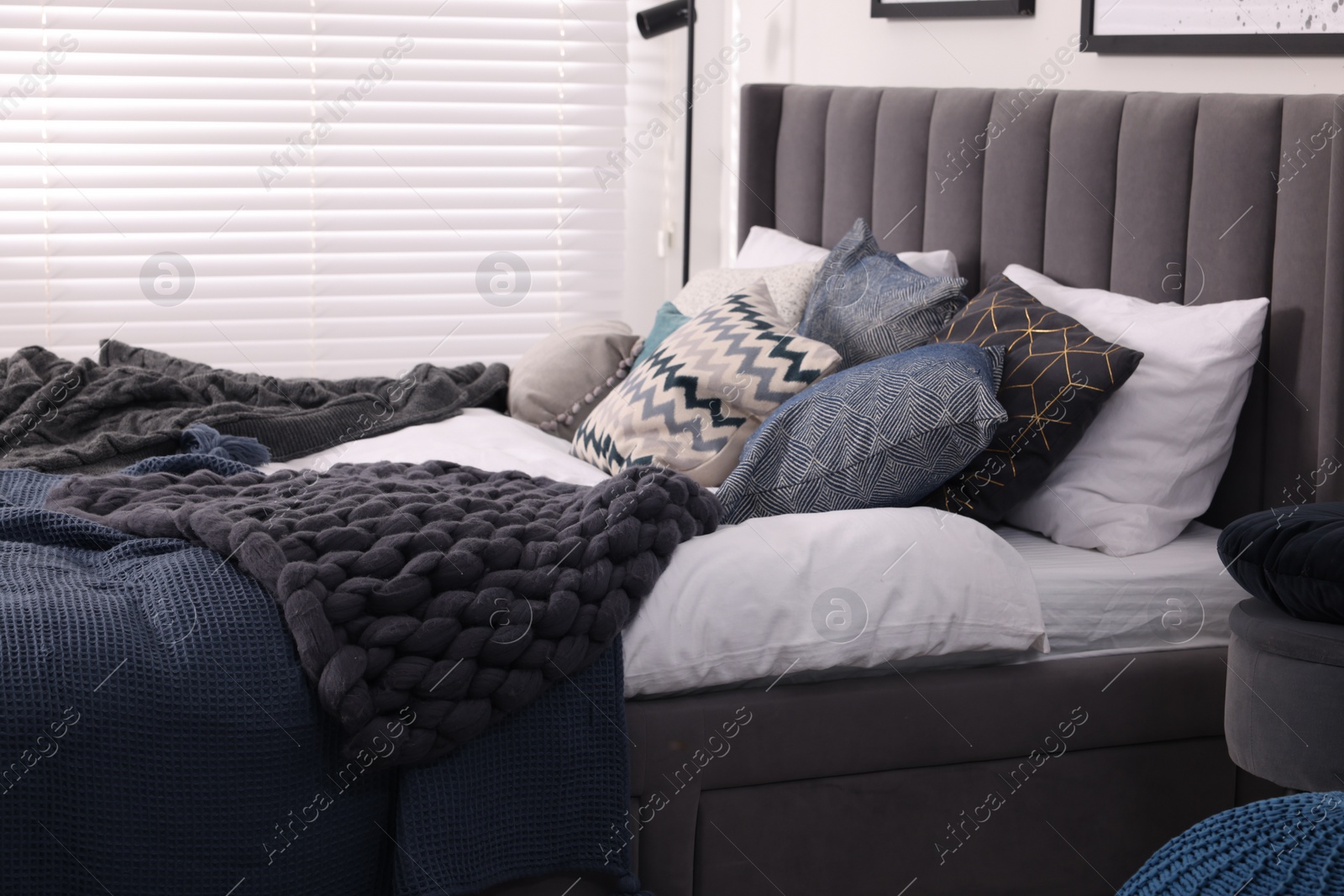 Photo of Large comfortable bed with soft pillows and blankets in room. Home textile