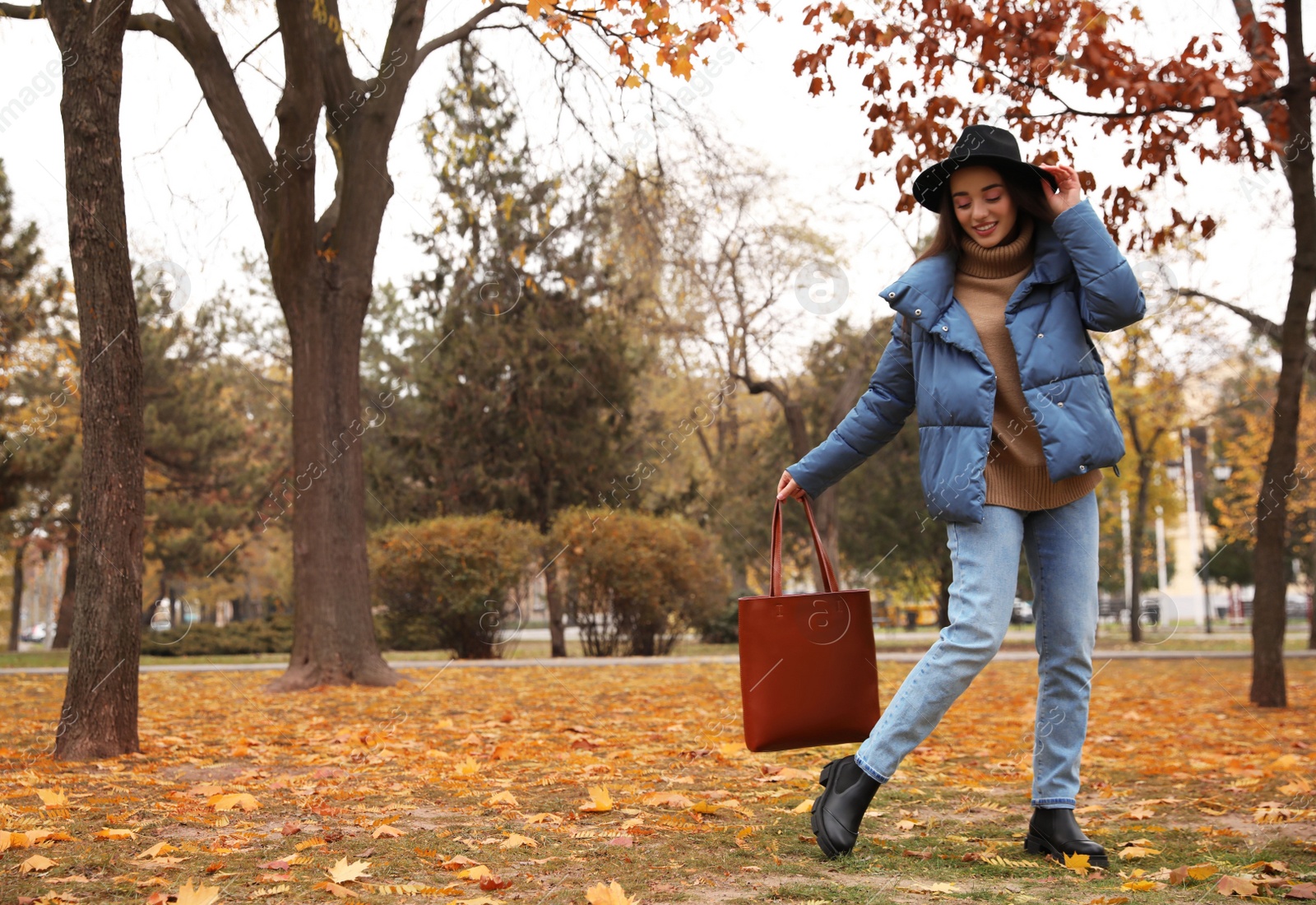 Photo of Young woman wearing stylish clothes in autumn park, space for text