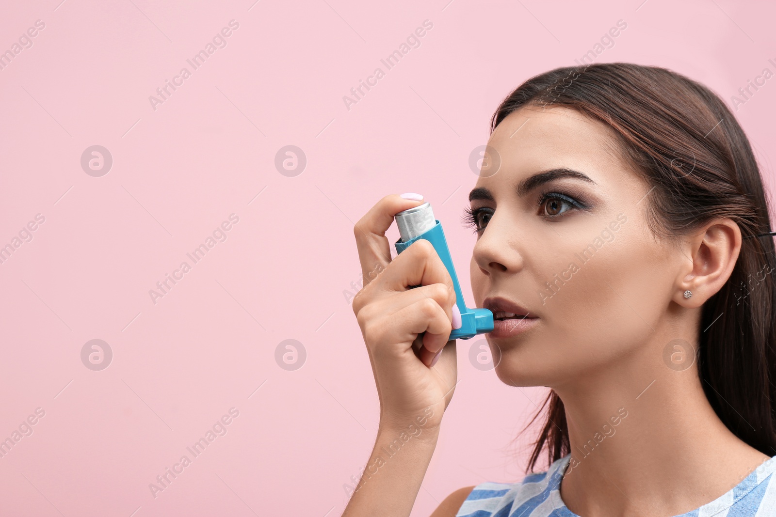 Photo of Young woman using asthma inhaler on color background. Space for text