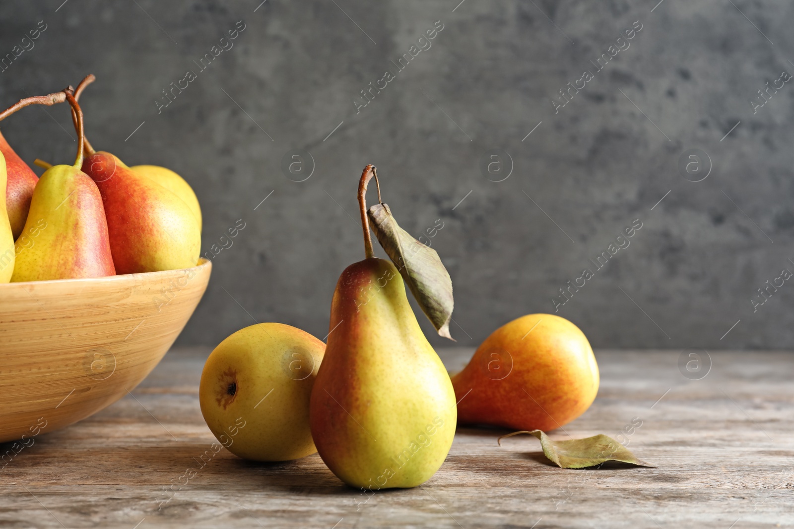 Photo of Ripe pears on wooden table against grey background