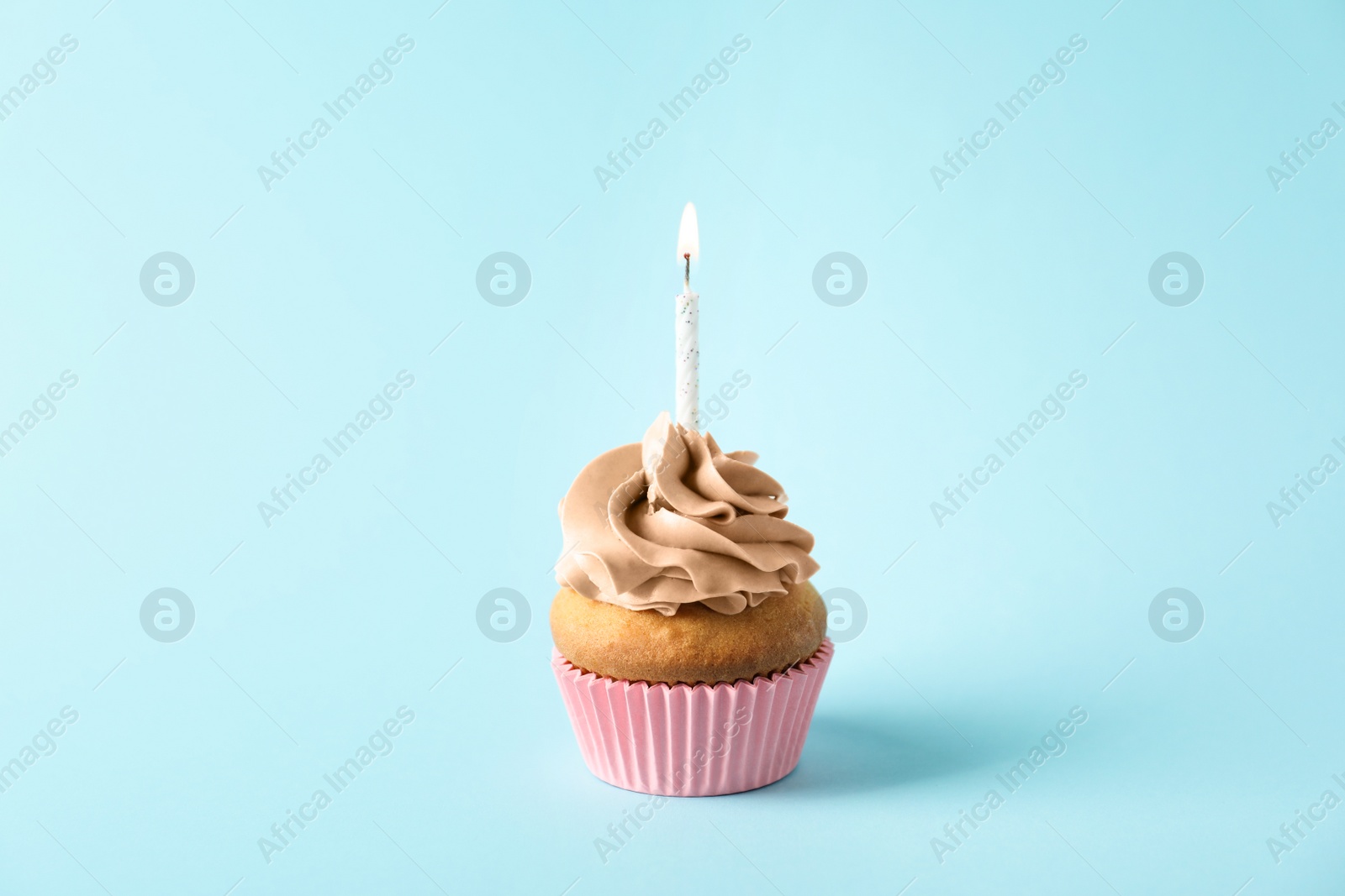 Photo of Delicious birthday cupcake with candle on color background