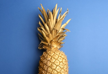 Golden pineapple on blue background, top view. Creative concept