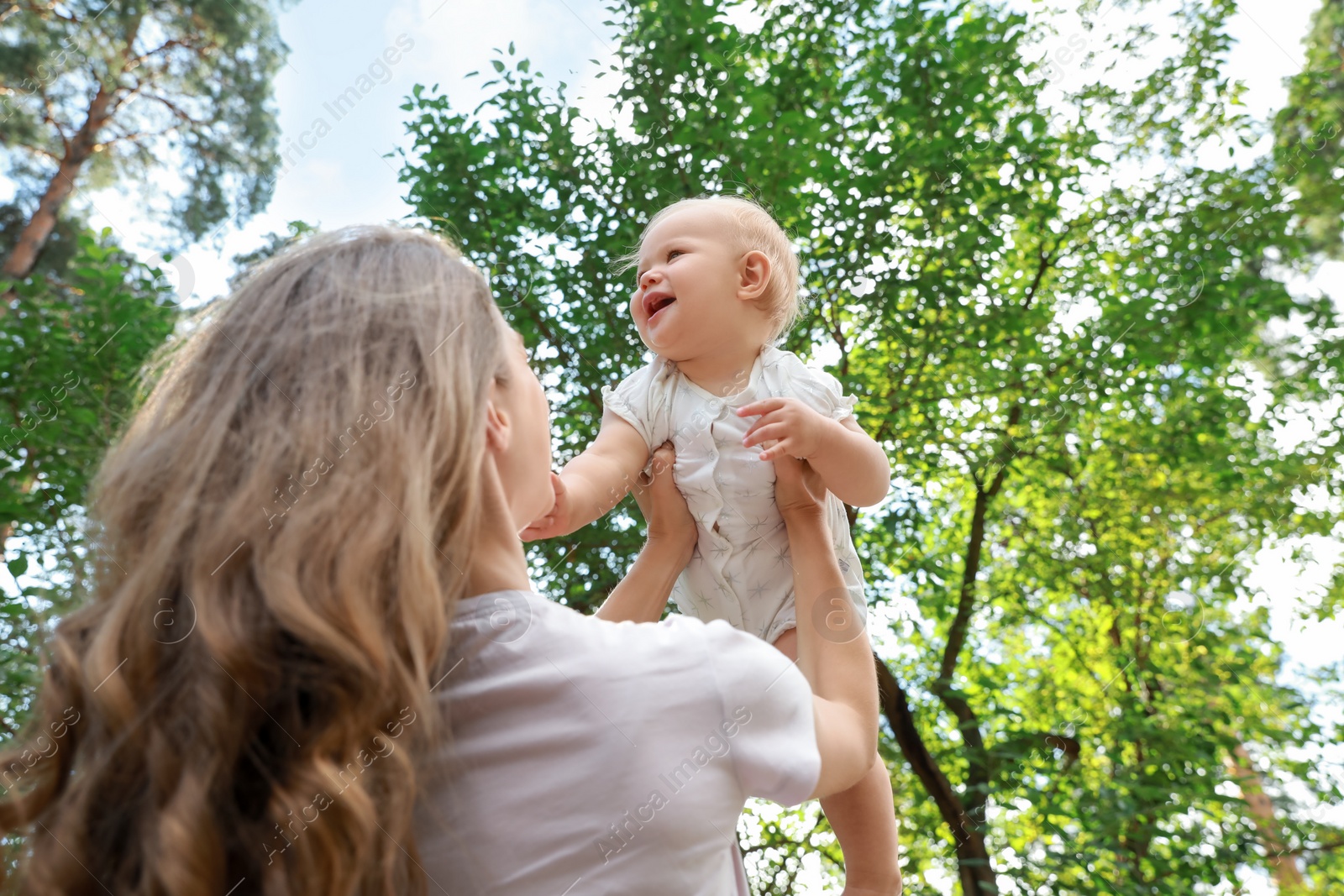 Photo of Mother with her cute baby spending time together outdoors, low angle view. Space for text