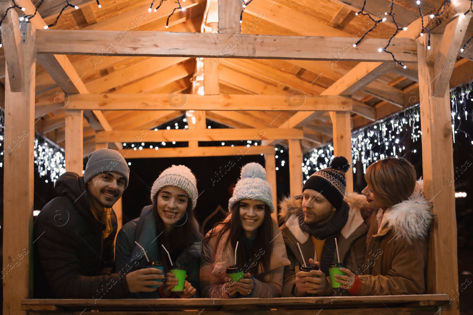 Photo of Happy friends with cups of mulled wine at winter fair