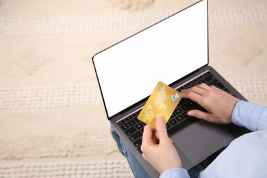 Online payment. Woman using credit card and laptop with blank screen, above view. Space for text