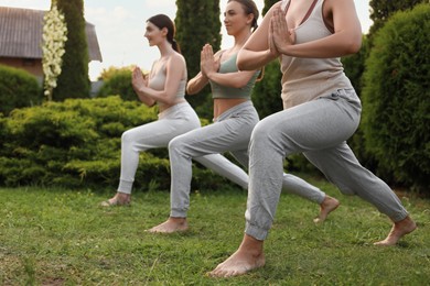 Photo of Group of young women practicing yoga outdoors, closeup