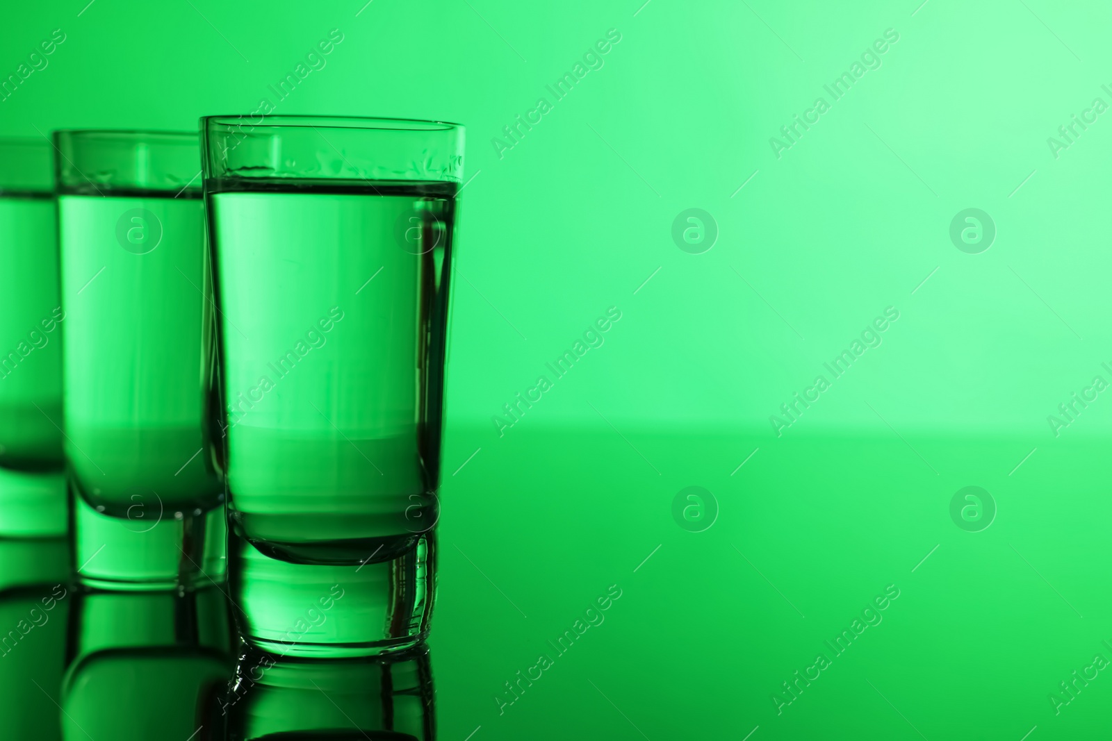 Photo of Vodka on table against green background, space for text