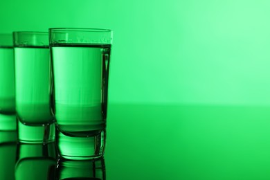 Photo of Vodka on table against green background, space for text