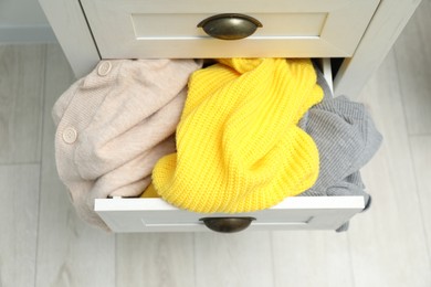 Cluttered chest of drawers indoors. Clothes in mess