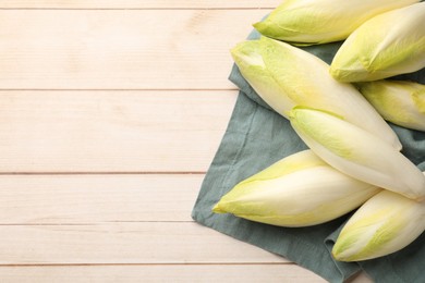 Photo of Raw ripe chicories on wooden table, top view. Space for text