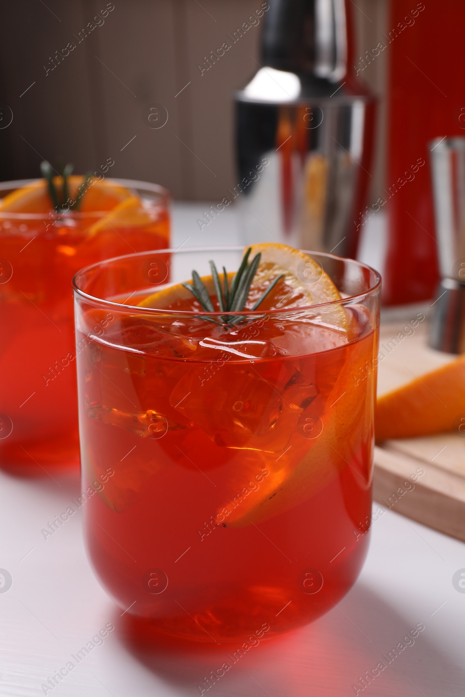 Photo of Aperol spritz cocktail, rosemary and orange slices on white wooden table, closeup