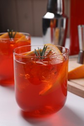 Photo of Aperol spritz cocktail, rosemary and orange slices on white wooden table, closeup