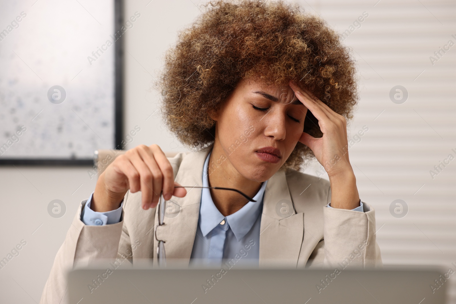 Photo of Young woman suffering from headache in office