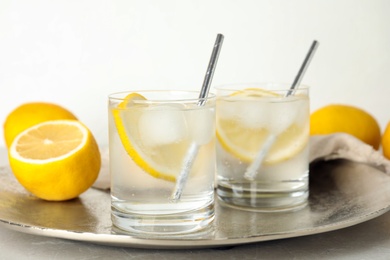 Soda water with lemon slices and ice cubes on silver tray
