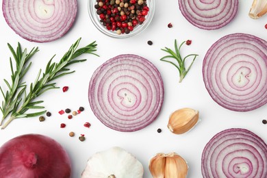 Fresh red onions, garlic, rosemary and spices on white background, flat lay