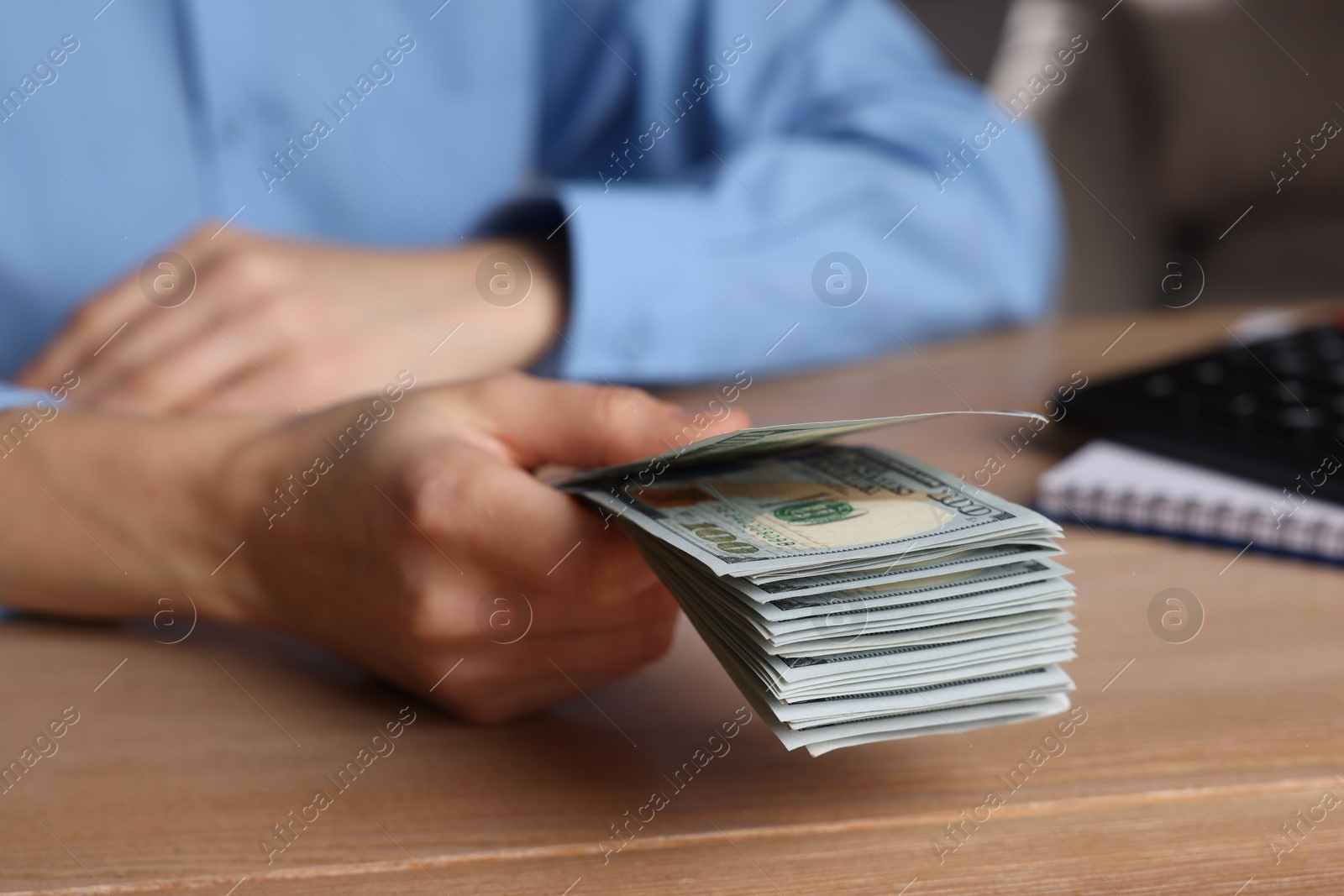 Photo of Money exchange. Woman holding dollar banknotes at wooden table, closeup