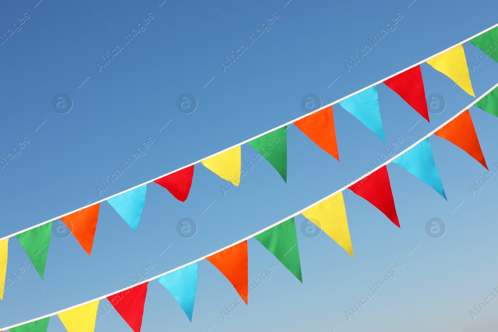 Photo of Buntings with colorful triangular flags against blue sky