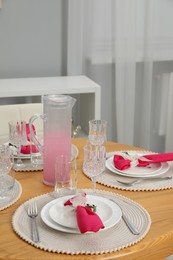 Photo of Color accent table setting. Glasses, plates, jug of beverage and pink napkins in dining room