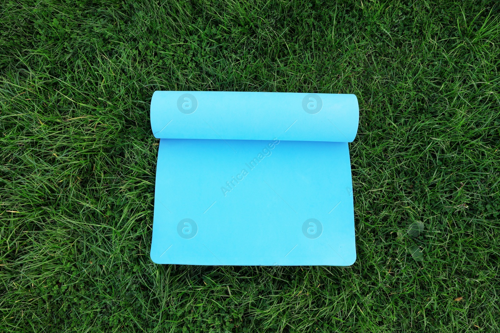 Photo of Blue karemat or fitness mat on fresh green grass outdoors, above view