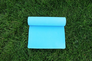 Blue karemat or fitness mat on fresh green grass outdoors, above view