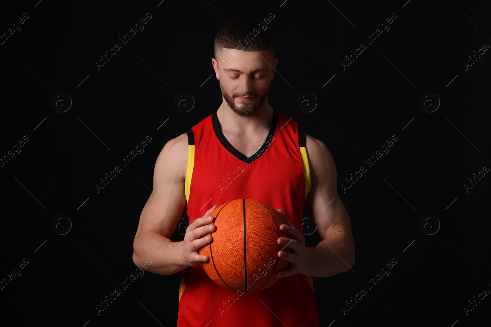 Photo of Athletic young man with basketball ball on black background