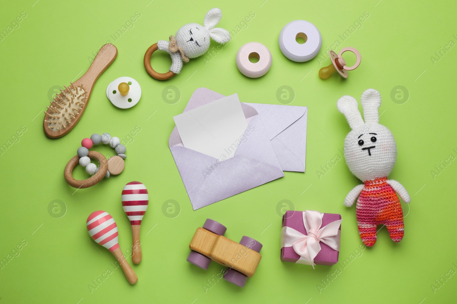 Photo of Envelopes for baby shower and accessories on light green background, flat lay