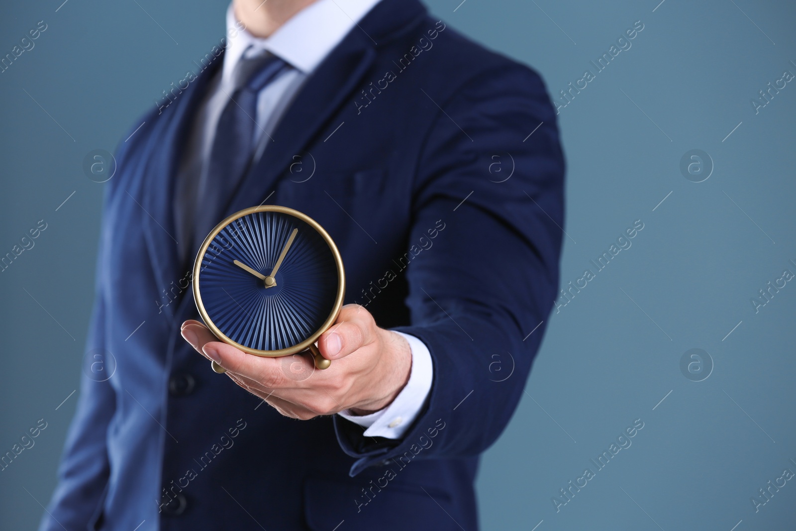 Photo of Businessman holding alarm clock on color background. Time concept