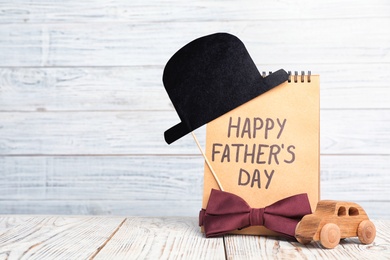 Paper hat, notebook and bow tie on wooden table with space for text. Father's day celebration