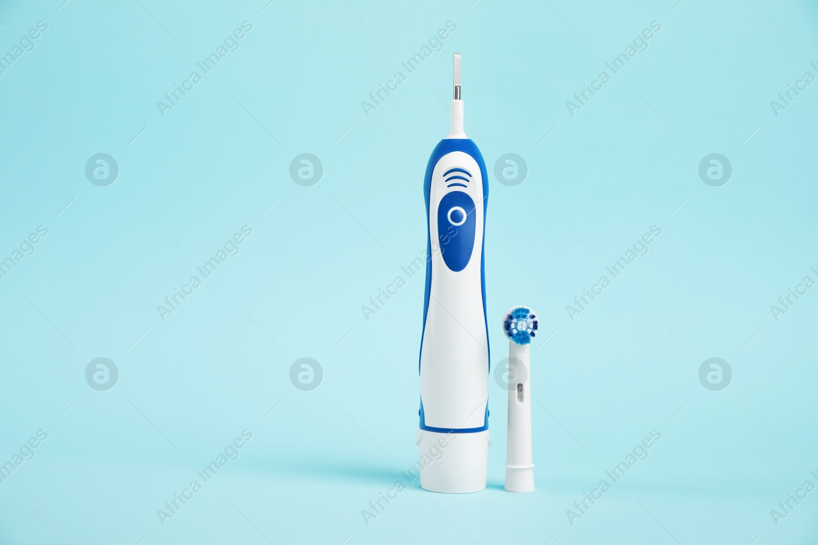 Photo of Electric toothbrush on light blue background, space for text