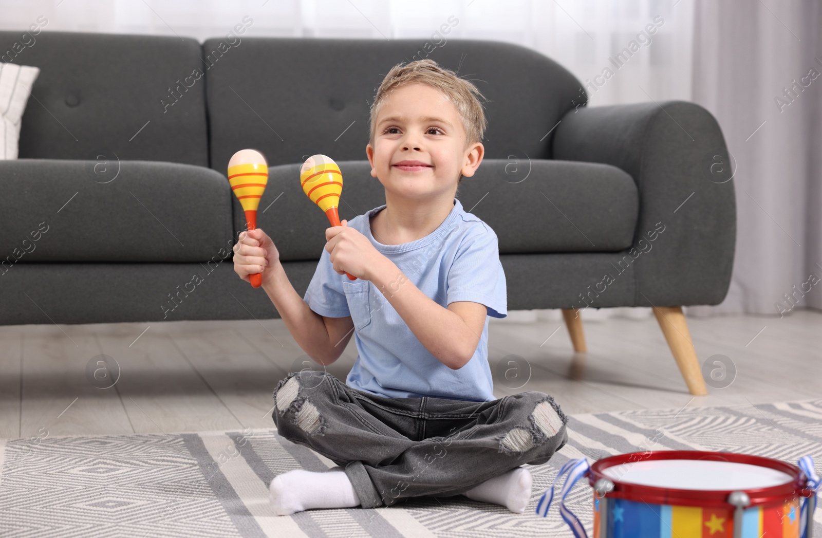 Photo of Little boy playing toy maracas at home