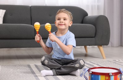 Little boy playing toy maracas at home