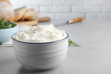Photo of Bowl of tasty cream cheese on grey table. Space for text