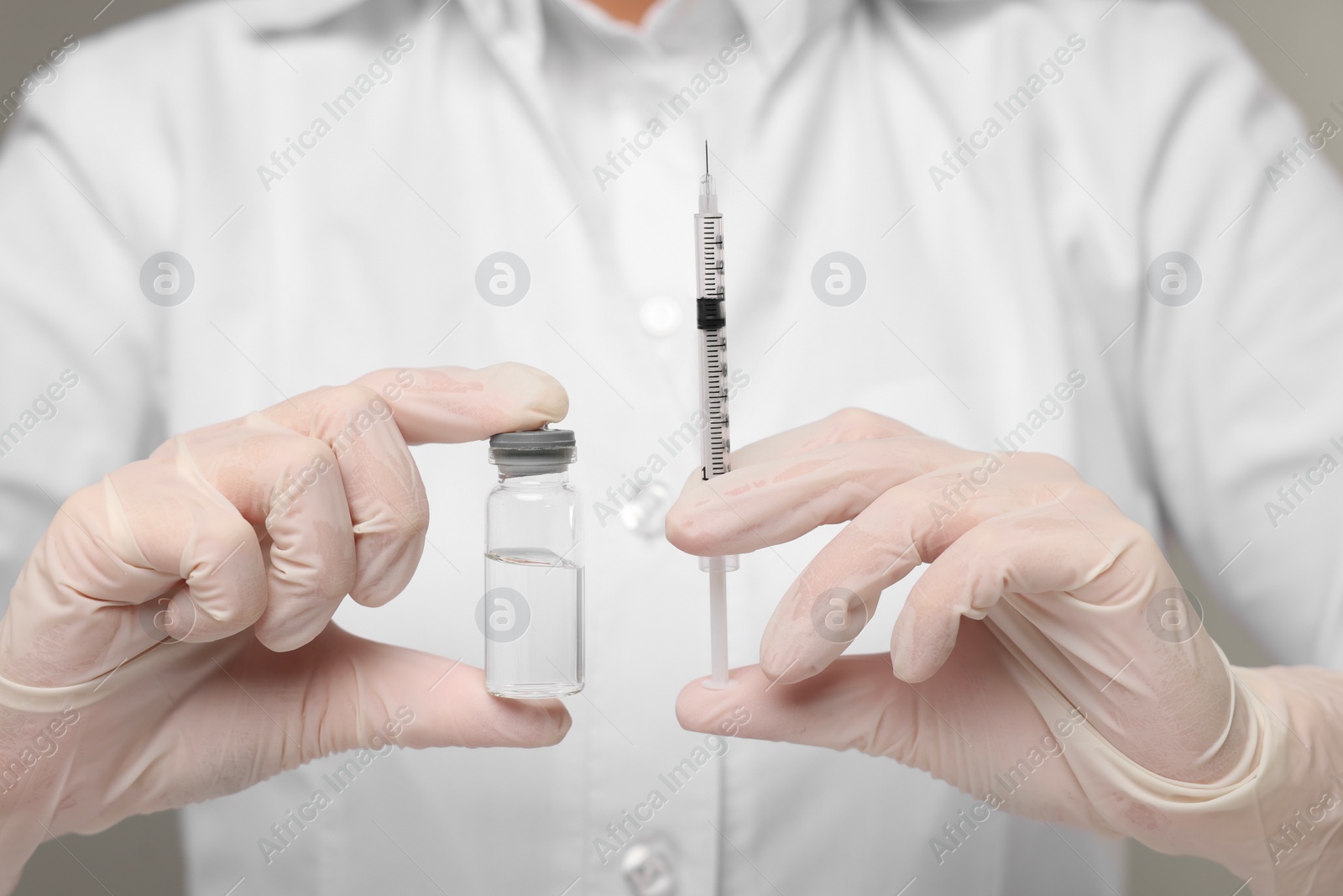 Photo of Doctor holding syringe and glass vial, closeup view