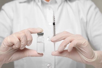 Doctor holding syringe and glass vial, closeup view