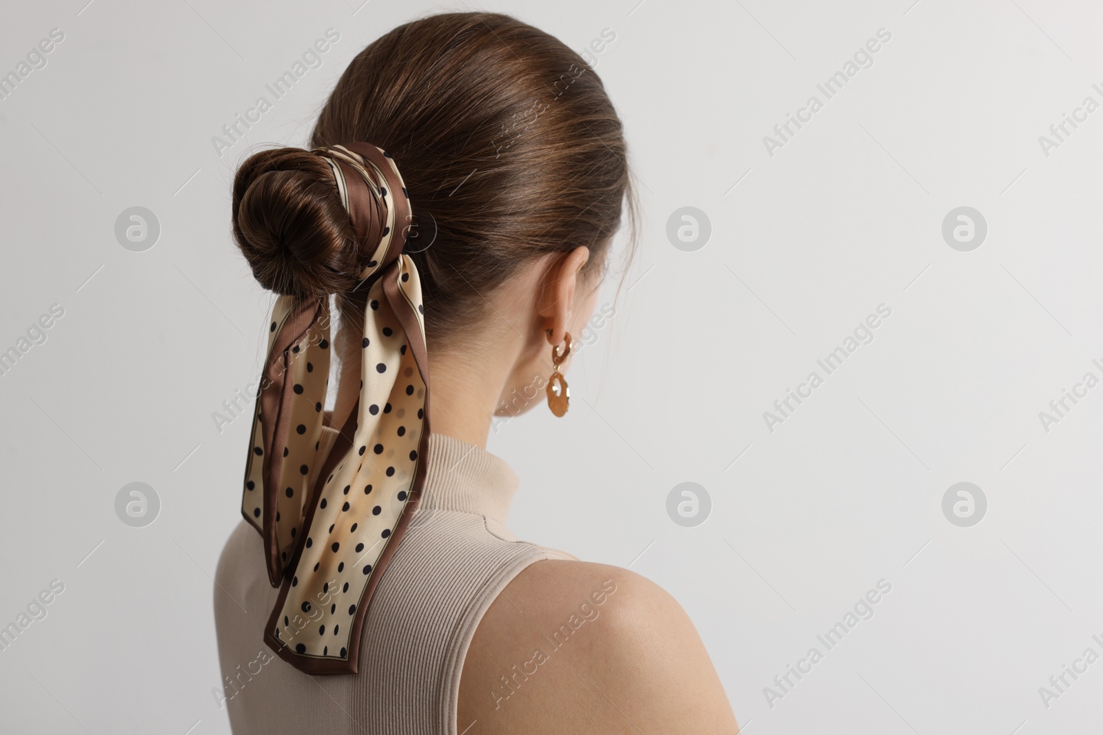 Photo of Young woman with stylish bandana on light background, back view. Space for text