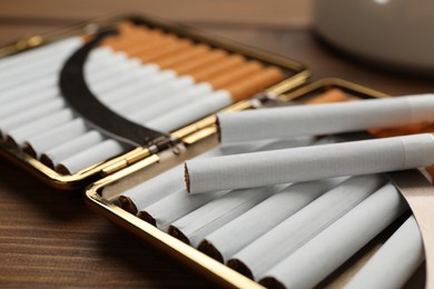 Stylish case with cigarettes on wooden table, closeup