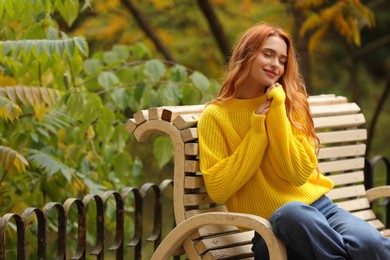 Beautiful woman sitting on bench in autumn park. Space for text