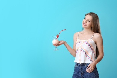 Young woman with glass of delicious milk shake on color background