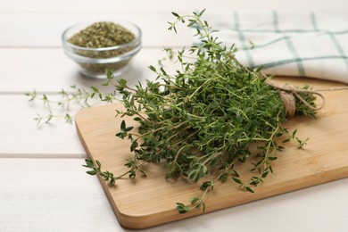 Photo of Bunch of aromatic thyme on white wooden table, closeup